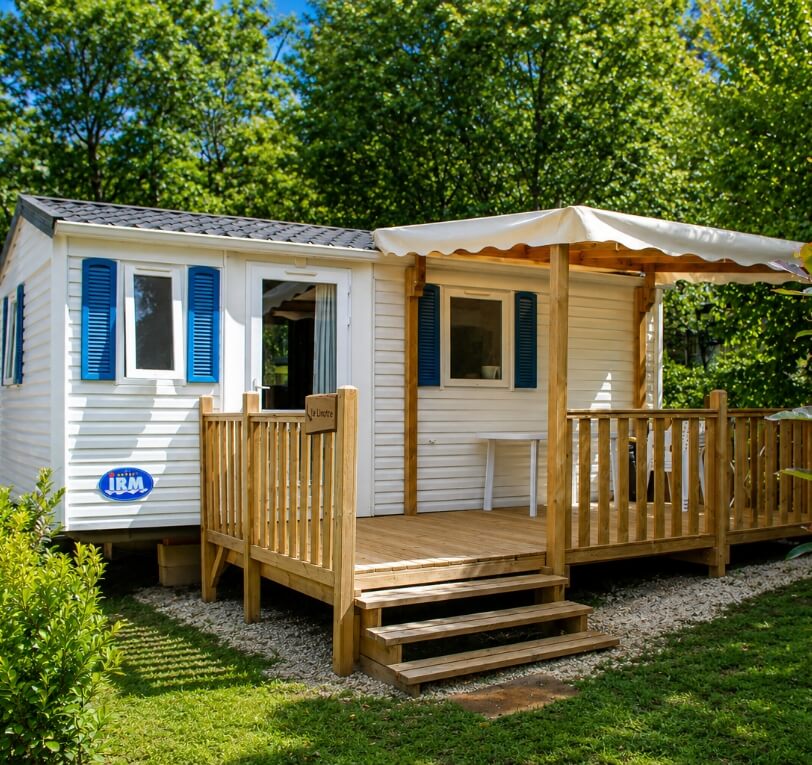 Exterior view of the ‘Le Laurier’ and ‘Le Palmier’ mobile homes available for hire at Le Bel Air campsite in the Lot, featuring a covered wooden terrace