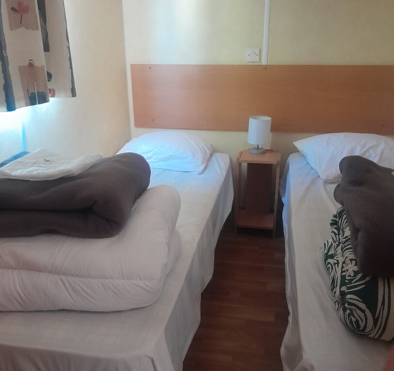 Room with two single beds in the ‘Le Laurier’ and ‘Le Palmier’ mobile homes available to rent at Le Bel Air campsite in the Lot