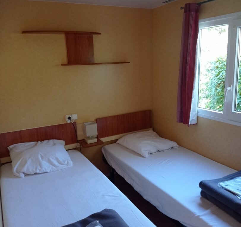 Room with two single beds in the ‘Le Figuier’ mobile homes available to rent at the campsite in the Lot, Le Bel Air